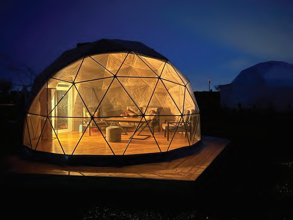 Geodesic dome glowing at night with panoramic transparent panels