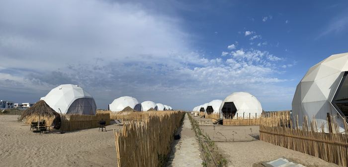 Row of glamping domes installed along a sandy beach